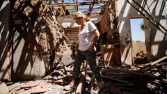 ロケット弾で損傷した家の内部を歩く女性＝イスラエル・スデロット