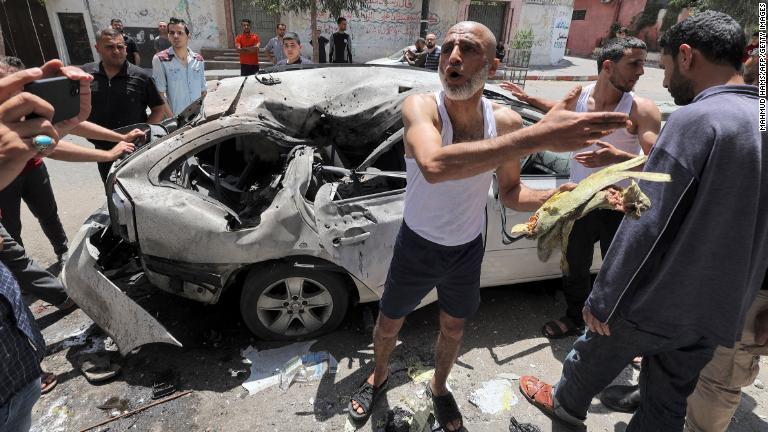 イスラエル軍の空爆によって損傷した車両を調べるパレスチナの人々＝１２日、ガザ地区/Mahmud Hams/AFP/Getty Images