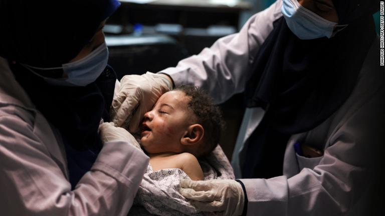 負傷した赤ちゃんを抱く看護師。赤ちゃんは空爆によって破壊された建物から救出された＝１５日、ガザ地区/Mahmud Hams/AFP/Getty Images
