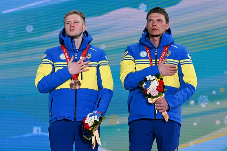 メダル授与式で胸に手を当てるＤ・スヤルコ選手（左）と伴走者のＯ・ニコノヴィチさん/Zhe Ji/Getty Images