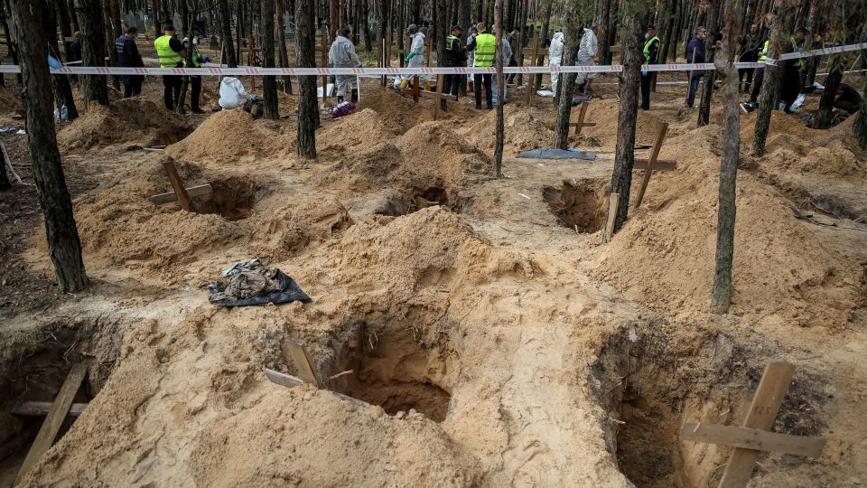 ウクライナ軍が解放した北東部イジュームで、集団埋葬地の調査を行う警察官と専門家/Gleb Garanich/Reuters