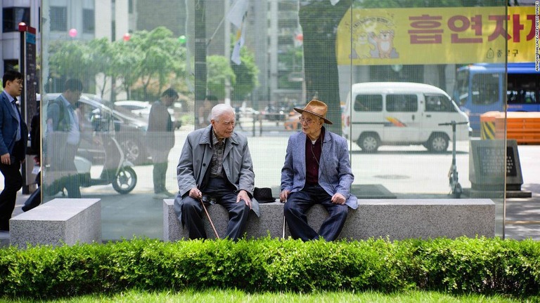 ベンチに座って会話する高齢男性＝韓国首都ソウル/Anthony Wallace/AFP/Getty Images