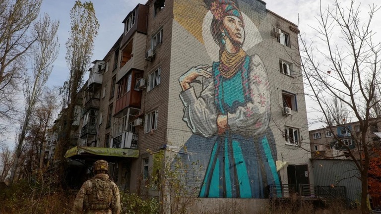 昨年１１月、前線の街アウジーイウカの損傷した建物の前を歩くウクライナ軍の兵士/Serhii Nuzhnenko/Radio Free Europe/Reuters