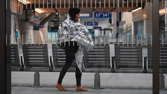 緊急用のブランケットを体にかけて電話をする女性。事件後、付近の駅は封鎖された