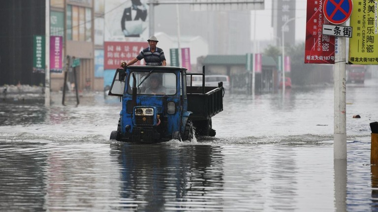 豪雨で冠水した道路を現地の人が車両で進んでいる＝１９日、中国ハルピン/Tao Zhang/Getty Images