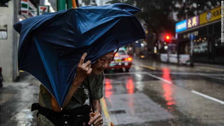 強風のなかタクシーを待つ男性＝１６日、香港/Anthony Wallace/AFP/Getty Images