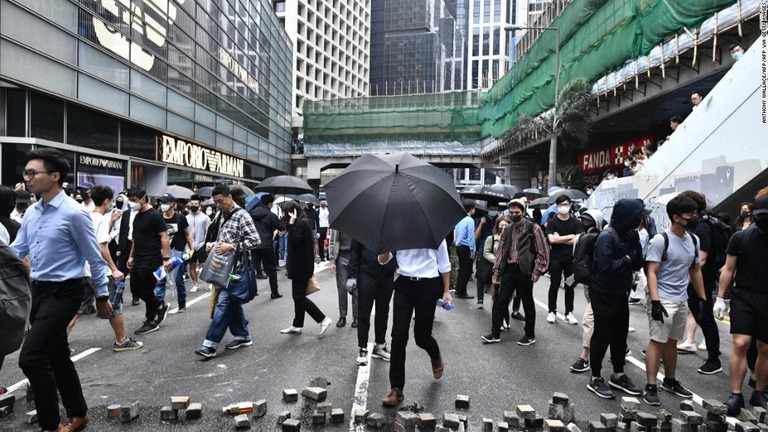 道路に置かれたれんがを避けて歩く人々＝１２日/ANTHONY WALLACE/AFP/AFP via Getty Images