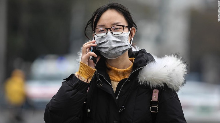 武漢市の市場を通り過ぎるマスクの女性＝１７日、武漢市/Getty Images/Getty Images