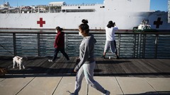 病院船「マーシー」の近くをマスクをして歩く人＝２７日、カリフォルニア州