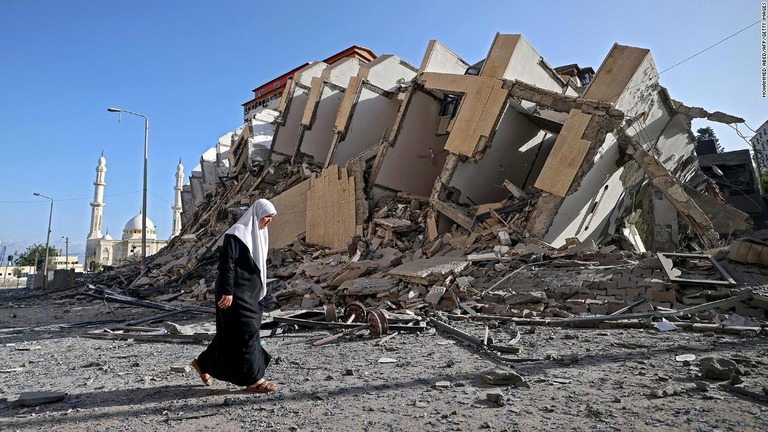 ガザ地区で破壊された建物の前を歩く女性＝１２日/Mohammed Abed/AFP/Getty Images