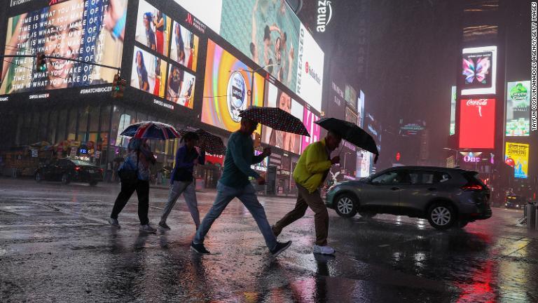 ニューヨーク市のタイムズスクエアで豪雨の歩く人々＝１日/Tayfun Coskun/Anadolu Agency/Getty Images