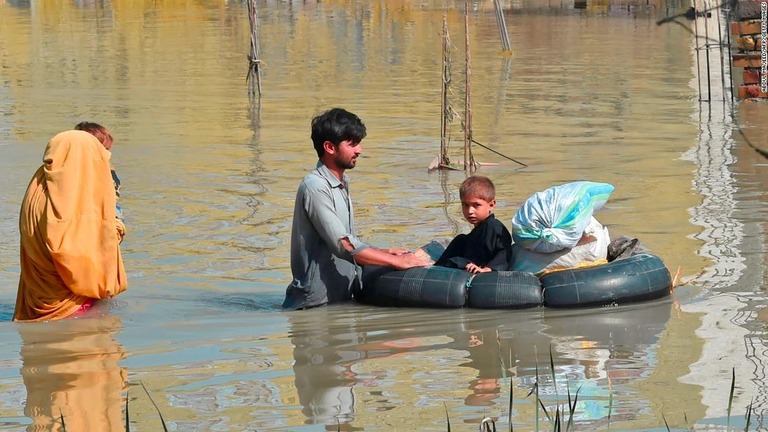 腰まで水に浸かりながらパキスタン北西部の被災地域を移動する家族/Abdul Majeed/AFP/Getty Images