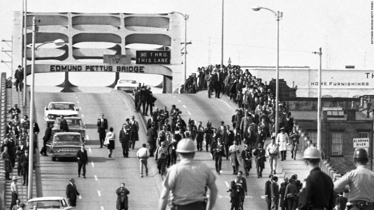 １９６５年の血の日曜日事件の数日前、州兵がアラバマ州セルマの川にかかる橋で更新する人々を見つめる様子/Bettmann Archive/Getty Images
