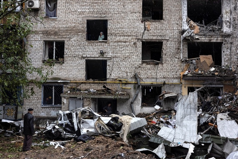 攻撃により破壊されたミコライウ州の住宅棟の被害を調べる人々/Umit Bektas/Reuters