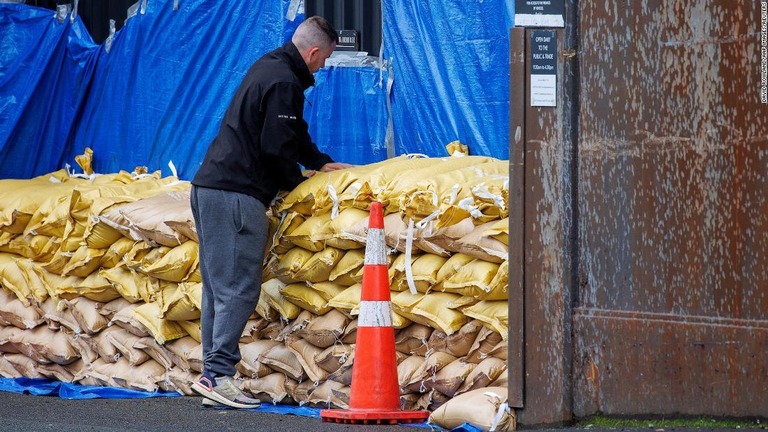 倉庫を守るために土のうを積み上げる男性＝１２日、ニュージーランド・オークランド/David Rowland/AAP Images/Reuters