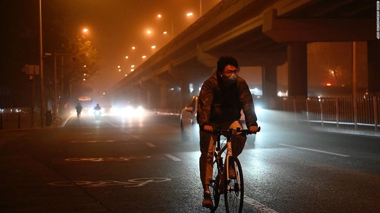 砂嵐のなか、自転車に乗る男性＝１０日、北京市/Jade Gao/AFP/Getty Images