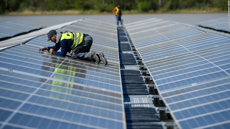 ドイツ西部の湖に浮かぶ太陽光発電所でソーラーパネルを修理する作業員/Ina Fassbender/AFP/Getty Images