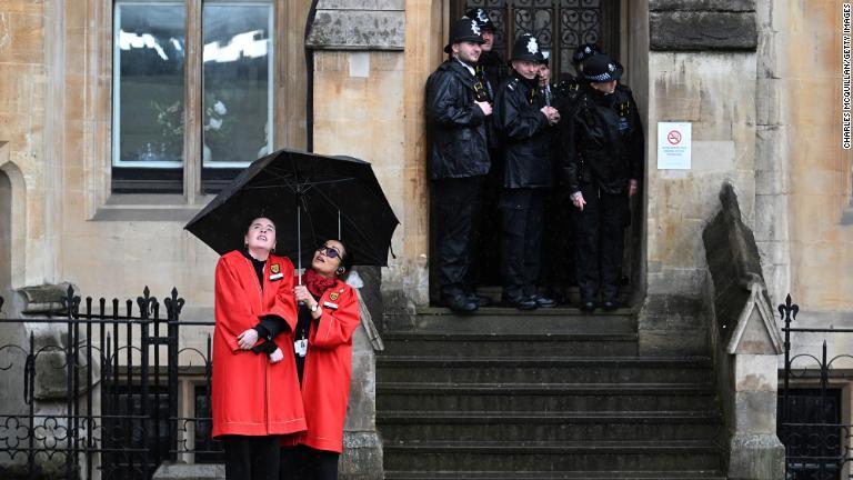 ５日、雨宿りする英国会議事堂の職員と警官/Charles McQuillan/Getty Images