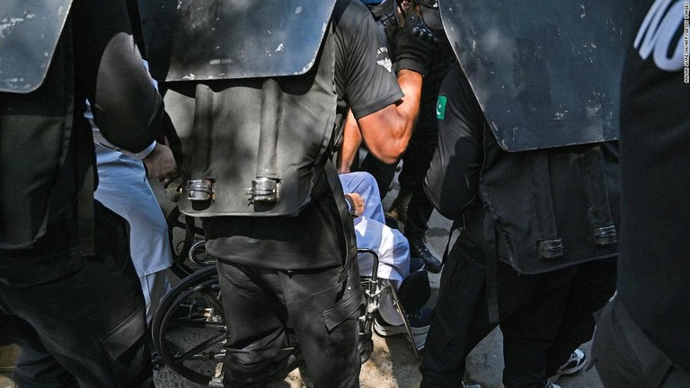 車椅子に乗り、治安要員に囲まれながら裁判所に現れたカーン氏/Aamir Qureshi/AFP/Getty Images