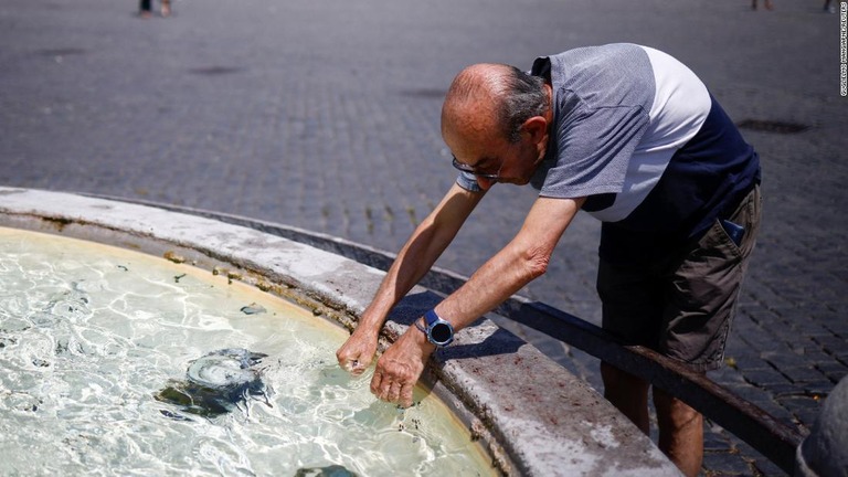 噴水の水で手を冷やす男性＝イタリア・ローマ/Guglielmo Mangiapne/Reuters