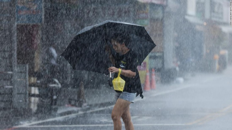 大雨のなか、傘をさして移動する女性/I-Hwa Cheng/AFP/Getty Images