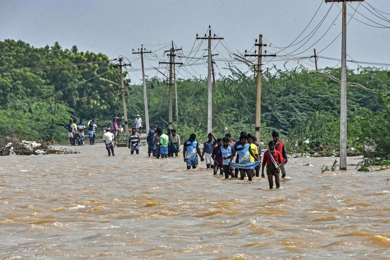 大雨で冠水した道路を歩く人々＝２０日、インド南部タミルナドゥ州トゥートクディ/Stringer/AFP/Getty Images