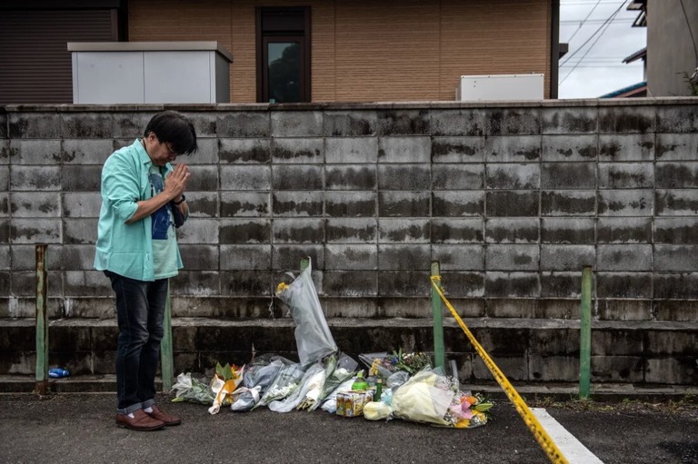 男性が京アニのスタジオ付近で花を手向けた後、いのりをささげる様子/Carl Court/Getty Images