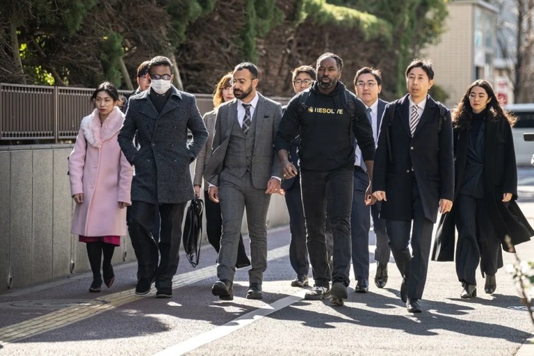 東京地裁の外を歩く原告３人と弁護団/Philip Fong/AFP/Getty Images