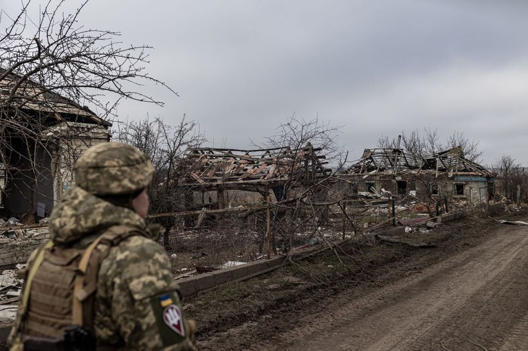 ロシア軍の砲撃で破壊された家屋の前を歩くウクライナ軍兵士/Diego Herrera Carcedo/Anadolu/Getty Images via CNN Newsource