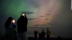 北極光を写真に収める人々＝１０日、英イングランド・ウィットリーベイ
