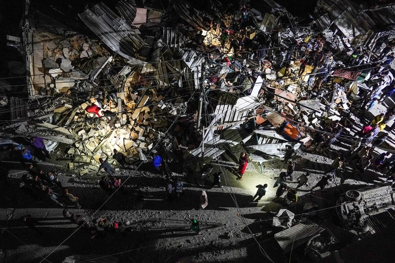 ヌセイラトへのイスラエルの空爆の後、瓦礫をかき分けて捜索するパレスチナの人々/Stringer/AFP/Getty Images