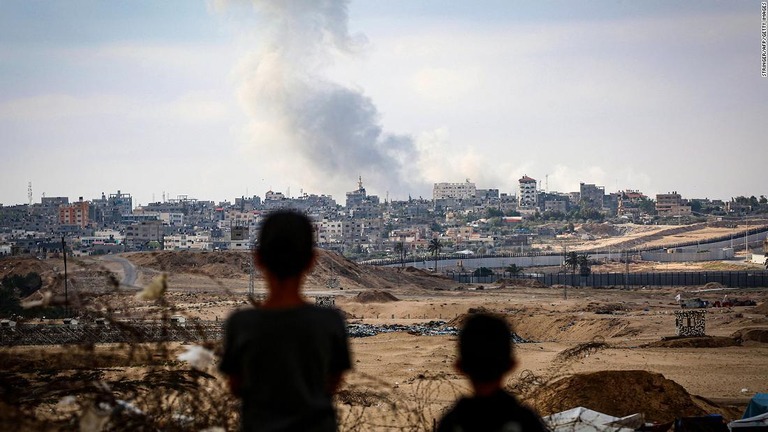 ガザ南部ラファへの空爆で立ち上る煙を眺める少年たち/Stringer/AFP/Getty Images