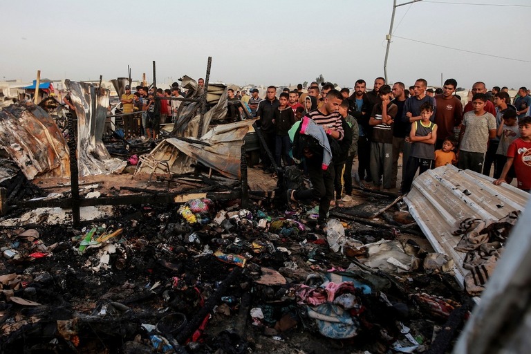 ガザ地区ラファで暮らすパレスチナ人らがイスラエルの攻撃による破壊の様子を見つめる/Jehad Alshrafi/AP