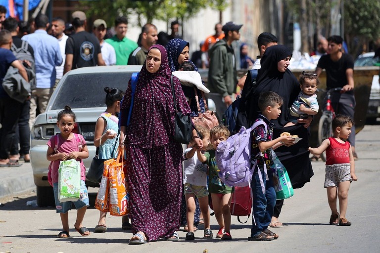 荷物を手にラファから避難する女性と子ども/AFP/Getty Images