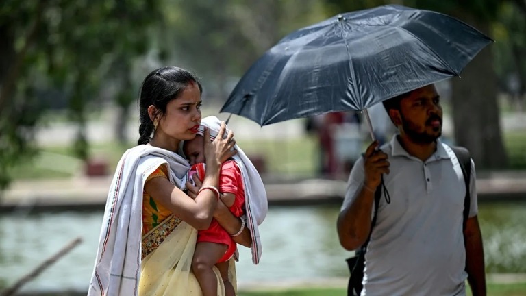 酷暑のニューデリーで我が子を日差しから守る女性/Money Sharma/AFP/Getty Images