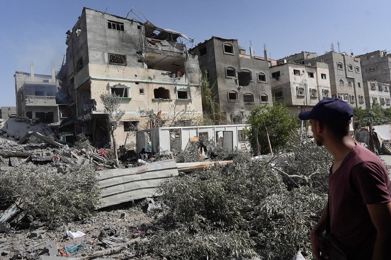 イスラエル軍によるガザ地区中部のヌセイラト難民キャンプへの軍事作戦後、建物の残骸を点検するパレスチナ人男性/Bashar Taleb/AFP/Getty Images