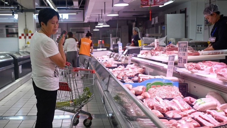 北京市内のスーパーで豚肉を吟味する買い物客/Wang Zhao/AFP/Getty Images