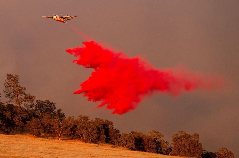 遅延剤を散布する航空機＝１７日、米カリフォルニア州カラベラス郡/Noah Berger/AP