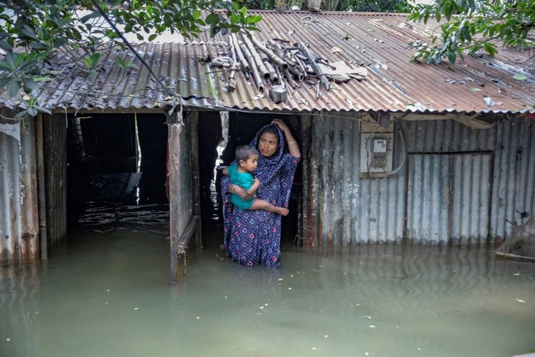 子どもを抱えて洪水に見舞われた家屋の前に立つ母親＝２０日、バングラデシュ・シレット/Salahuddin Paulash/Drik/Getty Images