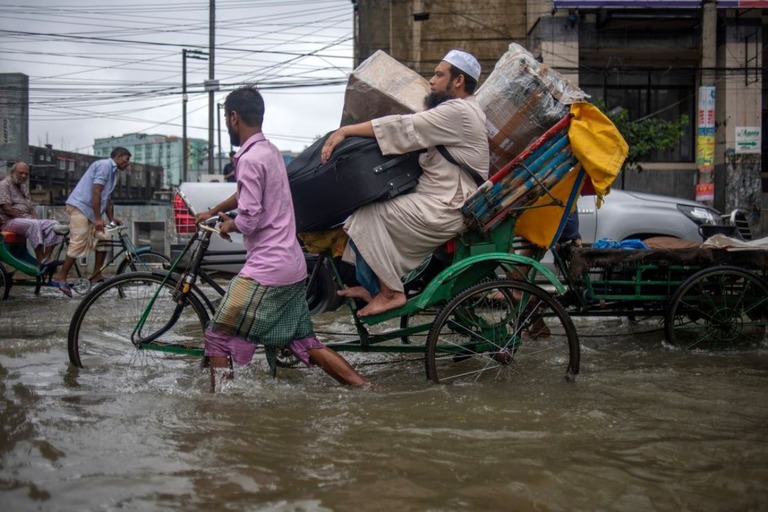 冠水した道路で荷物を運ぶ人たち＝２０日/Syed Mahamudur Rahman/NurPhoto/Getty Images