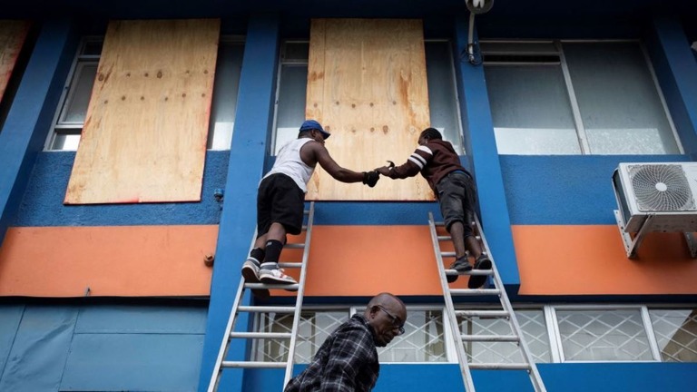 ハリケーン「ベリル」の接近に備え、窓を板で覆う作業員＝ジャマイカ・キングストン/Marco Bello/Reuters