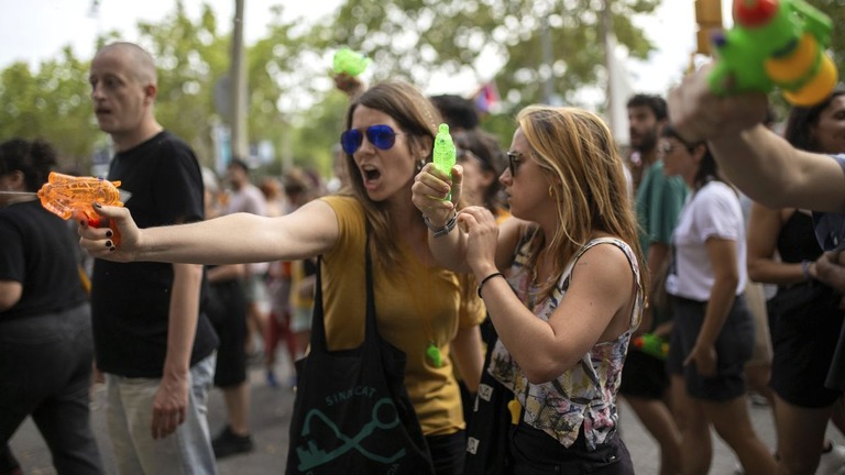 バルセロナを訪れた観光客に向けて水鉄砲を放つ抗議デモの参加者/Lorena Sopêna/Europa Press/AP
