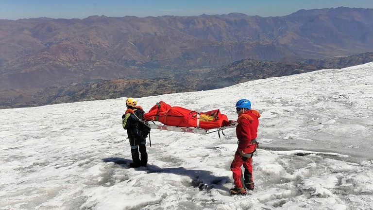 ２２年ぶりに発見された遺体を運んで雪山を歩く警官ら/Peruvian National Police/AP