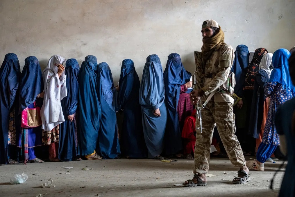 タリバンの兵士が警護する中、食料の配給に並ぶ女性たち＝カブール/Ebrahim Noroozi/AP/File