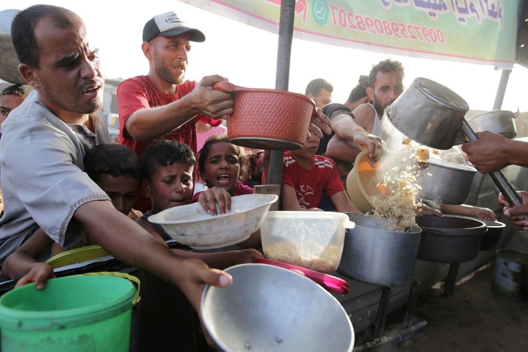 配給の食事を受け取るパレスチナの人々＝６月１５日、パレスチナ自治区ガザ地区ハンユニス/Jehad Alshrafi/AP