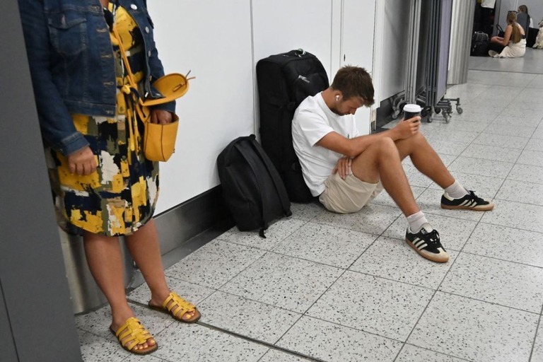 英ロンドン近郊のガトウィック空港で床に座って待機する旅行客＝２０日/Justin Tallis/AFP/Getty Images