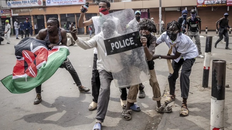 警察のシールドで催涙ガスから身を守るデモ参加者/Luis Tato/AFP/Getty Images