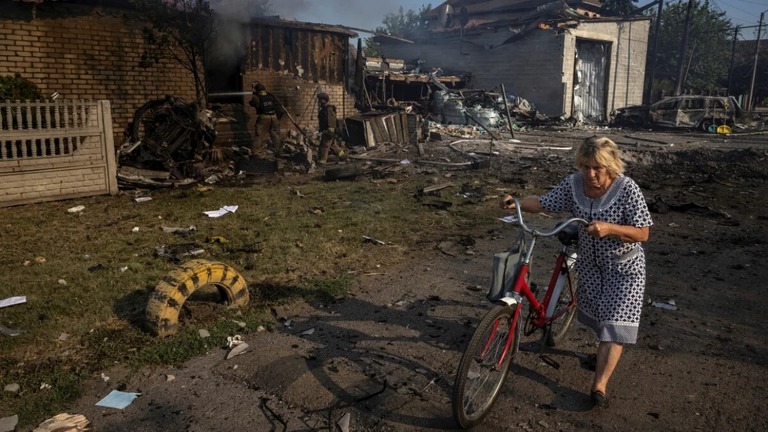 ロシアの攻撃で破壊された住宅のそばを通り過ぎる女性＝３日、ポクロウシクの住宅街/Thomas Peter/Reuters