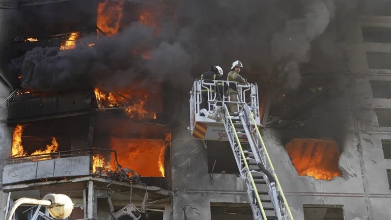 ロシア軍の空爆を受けた建物の消火にあたる消防隊＝１５日、ハルキウ/Andrii Marienko/AP