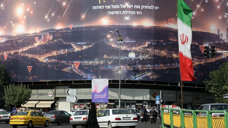 イラン国旗が掲げられたテヘランの街路を歩く人々/Fatemah Bahrami/Anadolu/Getty Images